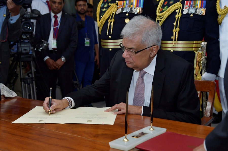 In this photo provided by Sri Lankan President's Office, Sri Lanka's newly elected president Ranil Wickremesinghe, signs after taking oath during his swearing in ceremony in Colombo, Sri Lanka, Thursday, July 21, 2022. - (Sri Lankan President's Office via AP)