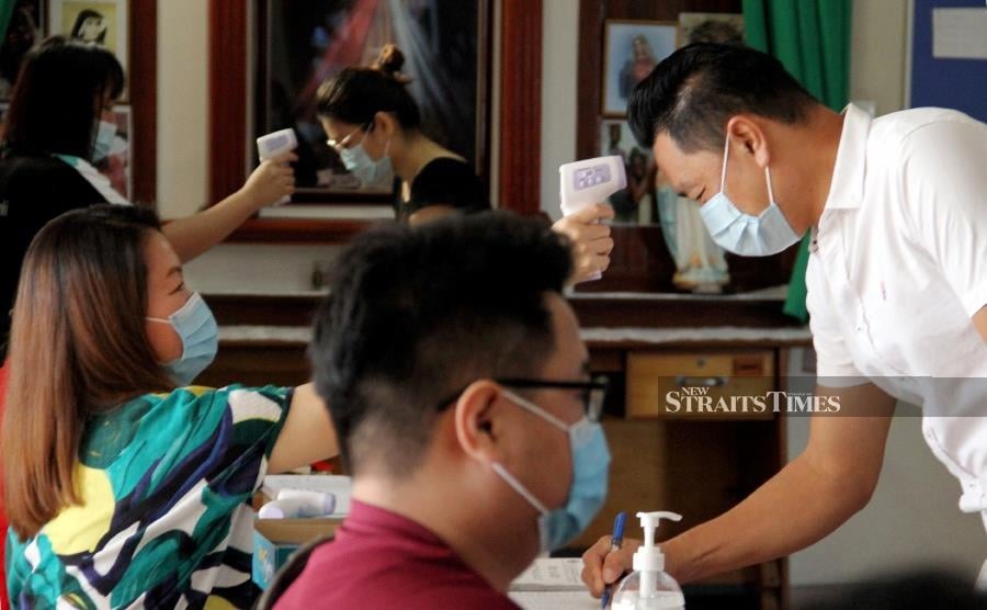 Staff at St Catherine's church checking temperatures of worshippers. -NSTP/MALAI ROSMAH TUAH.