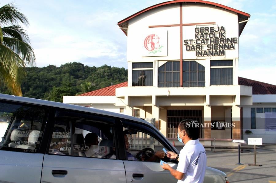 A staff at St Catherine's church  handing out numbered cards to worshippers. -NSTP/MALAI ROSMAH TUAH.