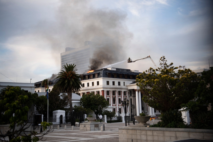 Firefighters attempt to extinguish a fire burning in the National Assembly, the main chamber of the South African Parliament buildings in Cape Town, on January 03, 2022. (Photo by RODGER BOSCH / AFP)