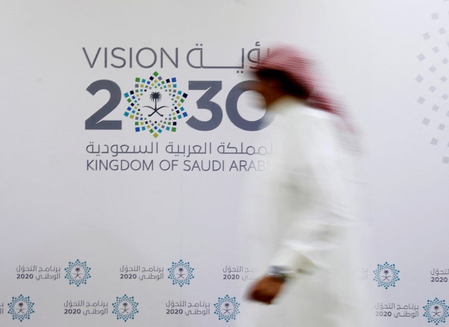A Saudi man walks past the logo of Vision 2030 after a news conference in Jeddah, Saudi Arabia June 7, 2016. REUTERS FILE PIC