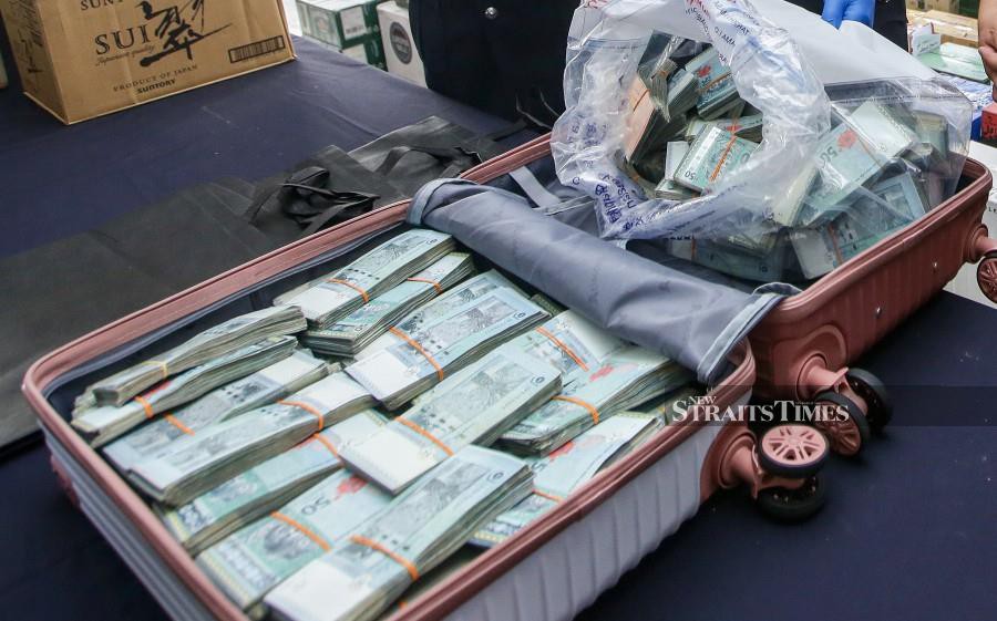 Police with the bag containing cash totalling more than RM500,000. -- NSTP Filepic