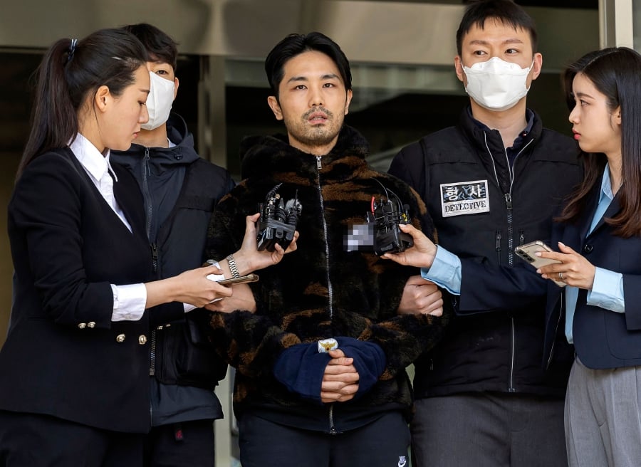 Lee Kyung-woo (centre), who was arrested on charges of kidnapping and murdering a woman, being escorted by authorities as he is transferred to the prosecution from a police station in Seoul. (Photo by Yonhap / YONHAP / AFP)