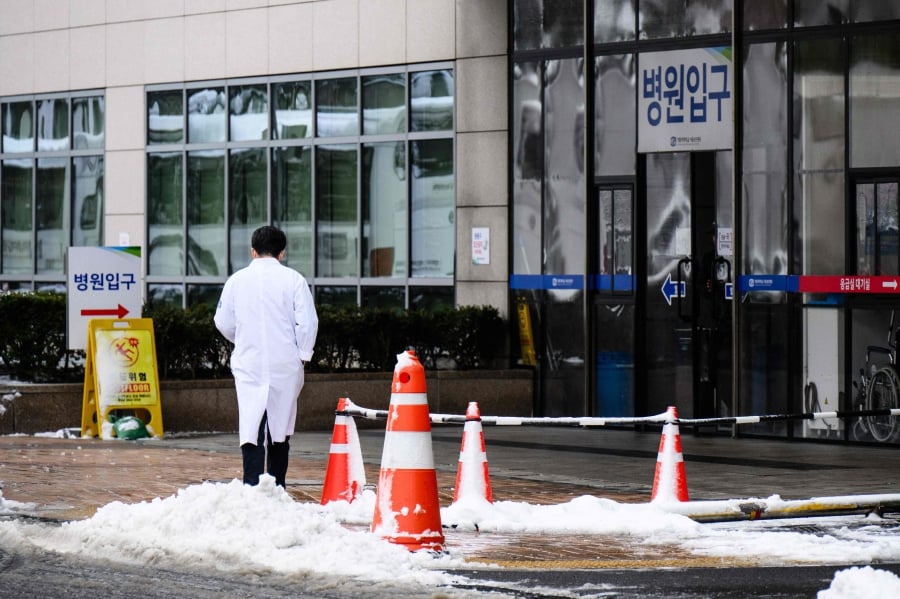 A medical worker walks towards the entrance of a hospital after snowfall in Seoul. (Photo by ANTHONY WALLACE / AFP)