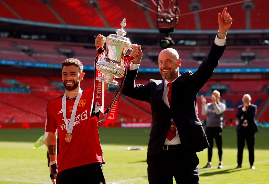 Manchester United's Bruno Fernandes and manager Erik ten Hag celebrate with the trophy after winning the FA Cup. REUTERS PIC