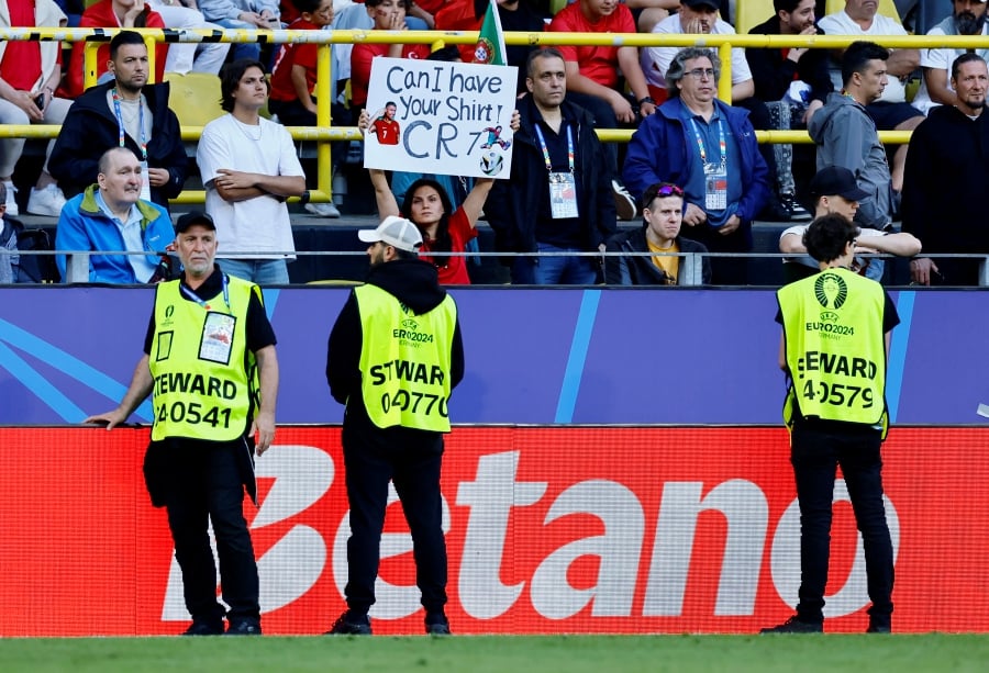 Portugal fan with a sign in support of Cristiano Ronaldo as stewards look on. (REUTERS/Leon Kuegeler)
