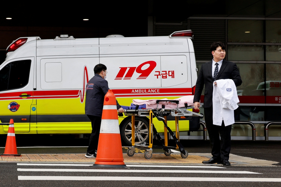 Ryu O. Hada (right) one of thousands of South Korean trainee doctors who resigned en masse to protest the government's medical policy, holds his white coat in front of the hospital where he worked in Seoul, South Korea. (REUTERS/Kim Soo-Hyeon)