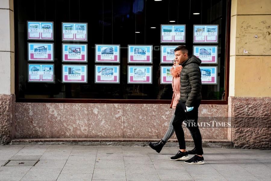 Young people walk past an estate agent. REUTERS/Vincent West/File Photo