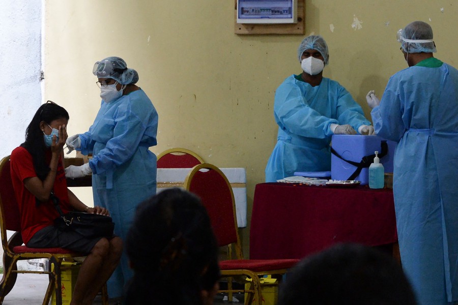 A health worker inoculates a woman with a dose of the Chinese-made Sinopharm Covid-19 coronavirus vaccine as government imposed travel restrictions and weekend lockdown to curb the spread of Covid-19 coronavirus in Colombo on May 16, 2021. (Photo by LAKRUWAN WANNIARACHCHI / AFP)