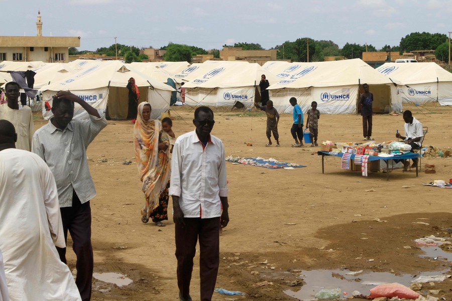 Sudanese who are already displaced by conflict, walk near tents at a makeshift campsite they were evacuated to following deadly floods in the eastern city of Kassala on Monday (Aug 12). — AFP