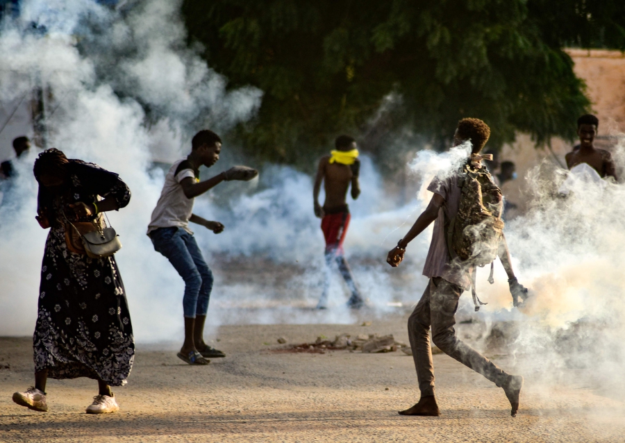 Sudanese youths confront security forces amidst tear gas fired by them to disperse protesters in the capital Khartoum, on October 27, 2021, amid ongoing demonstrations against a military takeover that has sparked widespread international condemnation. - Security forces today made sweeping arrests of protesters who kept up demonstrations in the capital and other cities against this week's military coup, while the international community ramped up punitive measures. (Photo by AFP)