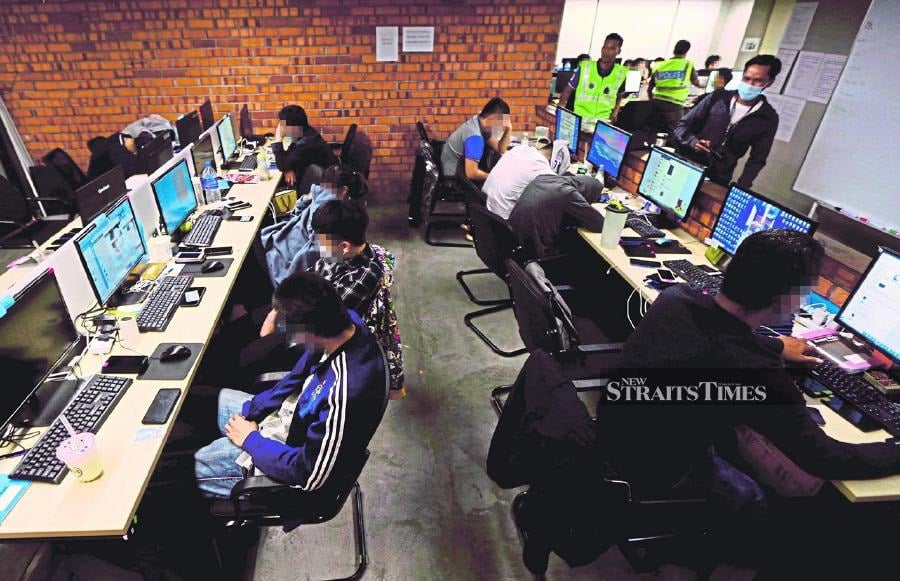 Police raiding a scam call centre in Kuala Lumpur in 2020. Consumers should not be solely responsible when they fall victim to a scam. -  File pic