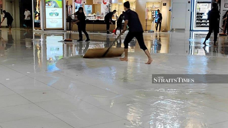Employees of Subang Parade shopping mall are working tirelessly to deal with a flash flood after water seeped into the building following a thunderstorm. - NSTP/ LUQMAN HAKIM
