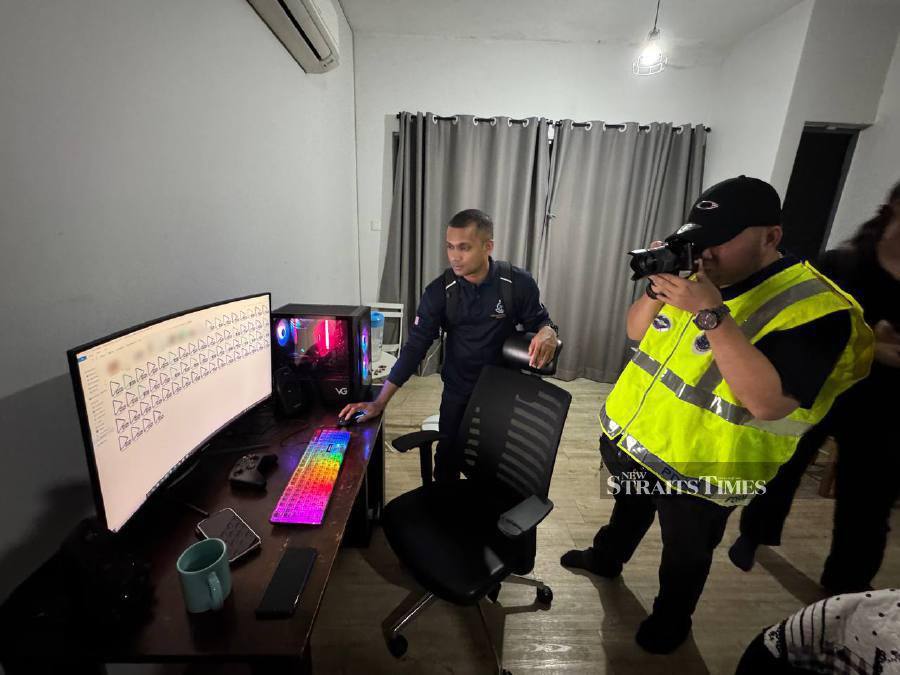 The raiding party inspecting suspicious files on the suspect’s computer. They found more than 3,500 porn materials, including some suspected to be CSAM. - Pic courtesy of police