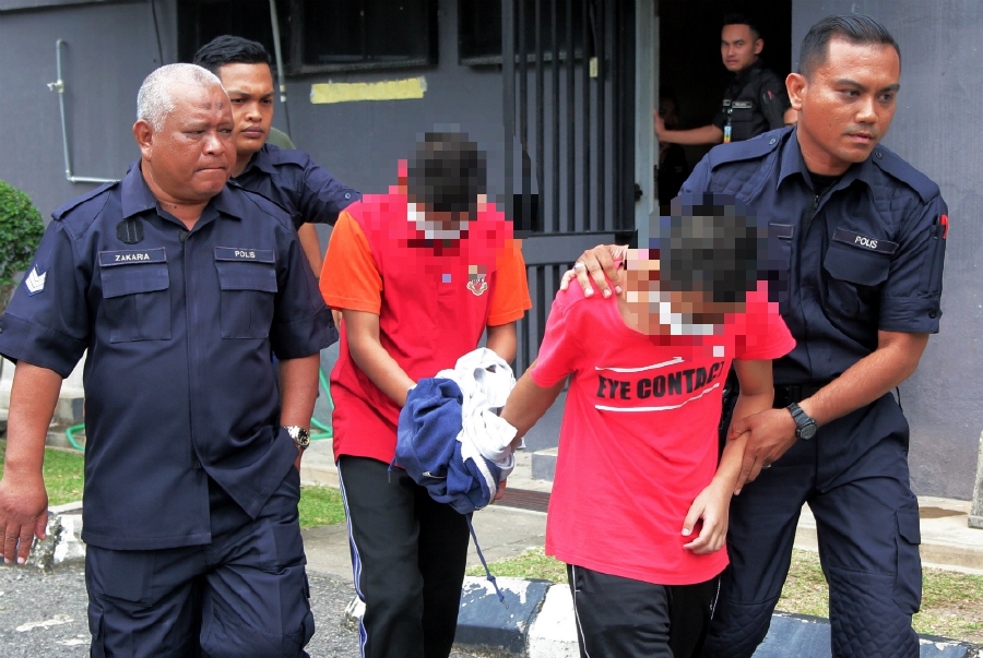 Two teenagers accused of murdering a 7-year-old tahfiz pupil being escorted from the magistrate’s court in Temerloh yesterday. BERNAMA PIX