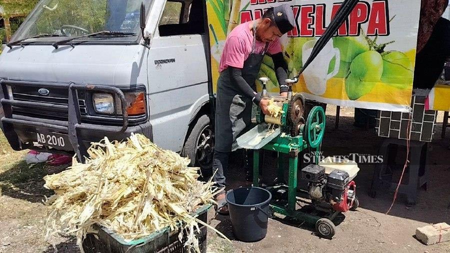 Mohd Yusri Yusof, 38, who sells coconut and sugarcane juices, is enjoying a brisk business as consumers prefer natural drinks to quench their thirst as the mercury climbs.- NSTP/ZULIATY ZULKIFFLI