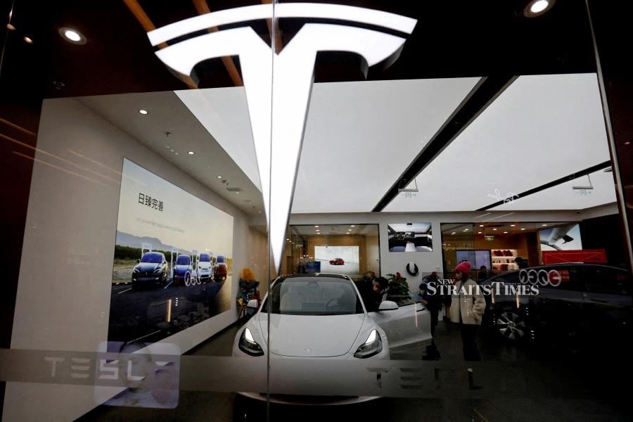 FILE PHOTO: Visitors check a Tesla Model 3 car next to a Model Y displayed at a showroom of the U.S. electric vehicle (EV) maker. REUTERS/Florence Lo/File Photo