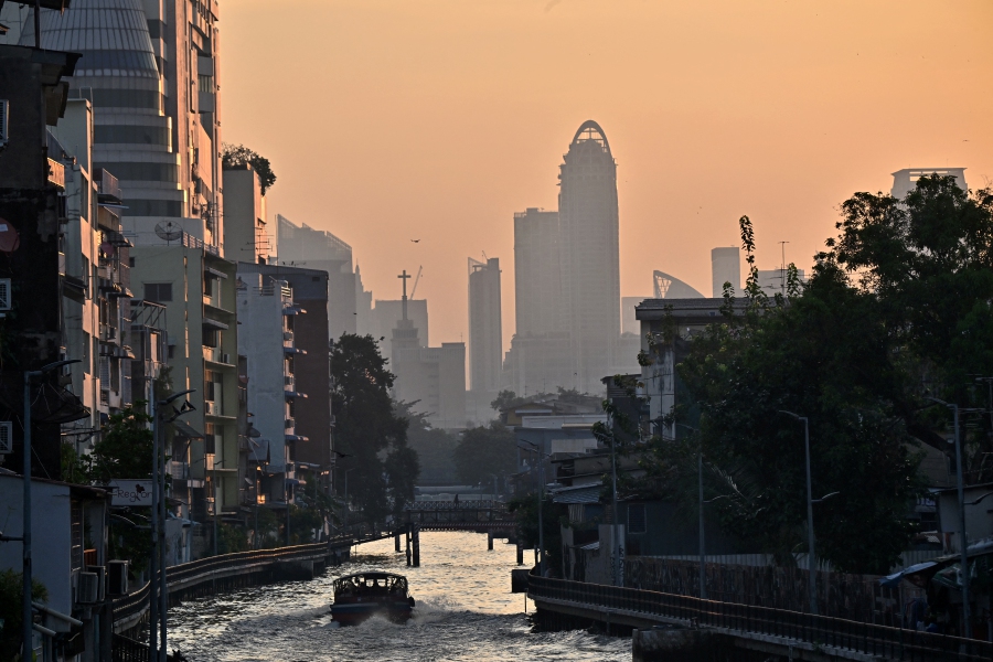 A commuter boat navigates a canal amid moderate levels of air pollution in Bangkok. (Photo by Lillian SUWANRUMPHA / AFP)