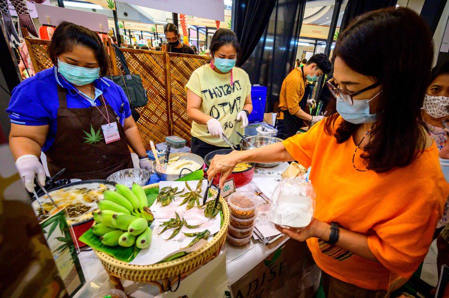 A customer buys fried cannabis leaves at the "Ganja & Thai Traditional Medicine in the City" fair in Bangkok. - AFP Pic