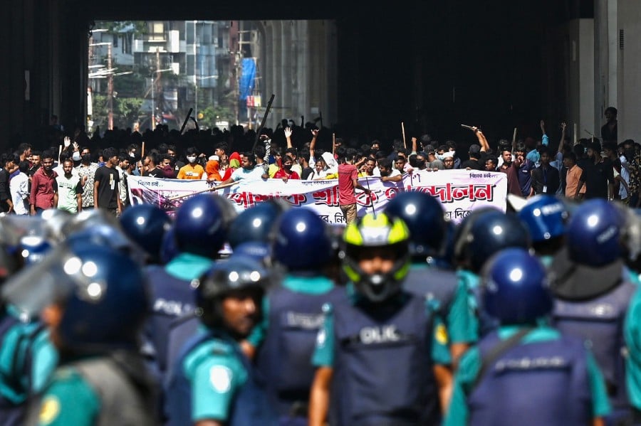 Bangladesh police (foreground) stand guard as garment workers protest to demand the increase of their salaries, in Dhaka on November 2, 2023. AFP PIC