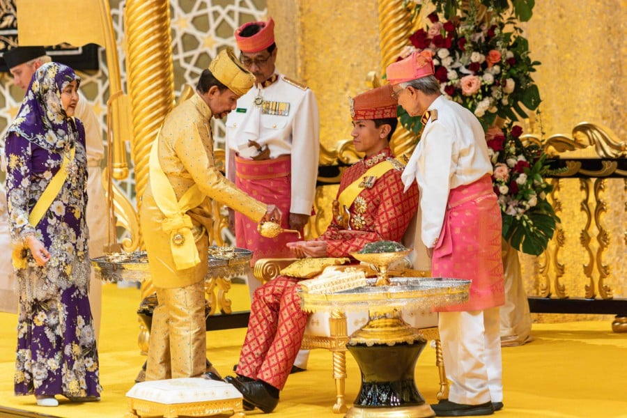 Brunei's Sultan Hassanal Bolkiah (2nd L) pouring scented oil on the hands of Prince Abdul Mateen during the royal powdering ceremony at Istana Nurul Iman, ahead of his wedding to Anisha Rosnah, in Bandar Seri Begawan, as Queen Raja Isteri Pengiran Anak Hajah Saleha (L) looks on. AFP PIC