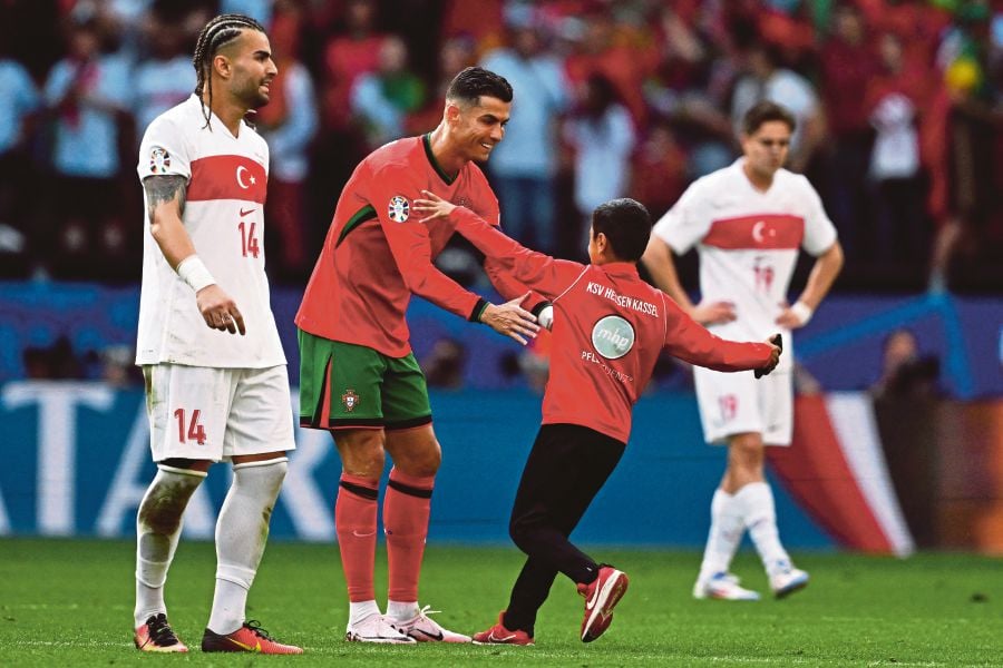 Portugal's forward Cristiano Ronaldo greets a young pitch invader during the UEFA Euro 2024 Group F football match between Turkey and Portugal at the BVB Stadion in Dortmund. (Photo by PATRICIA DE MELO MOREIRA / AFP)