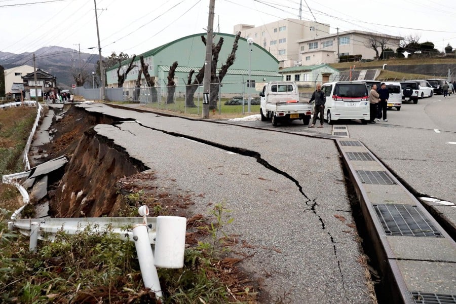People stand next to large cracks in the pavement after evacuating into a street in the city of Wajima, Ishikawa prefecture on January 1, 2024, after a major 7.5 magnitude earthquake struck the Noto region in Ishikawa prefecture in the afternoon. AFP PIC