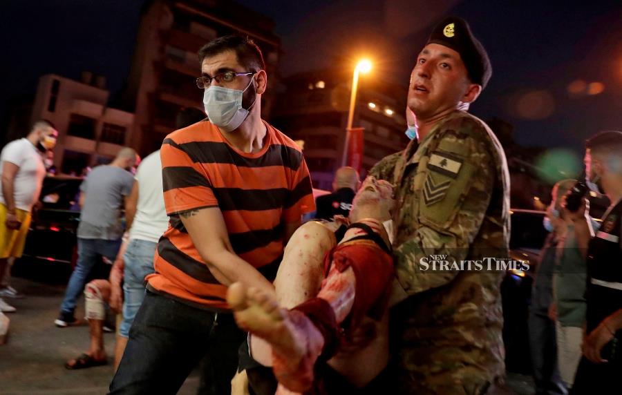 A Lebanese army soldier and a man carry away an injured man at a hospital in the aftermath of an explosion at the port of Lebanon's capital Beirut yesterday. - Two huge explosion rocked the Lebanese capital Beirut, wounding dozens of people, shaking buildings and sending huge plumes of smoke billowing into the sky. The cause of the explosion was not immediately known. (Photo by IBRAHIM AMRO / AFP)