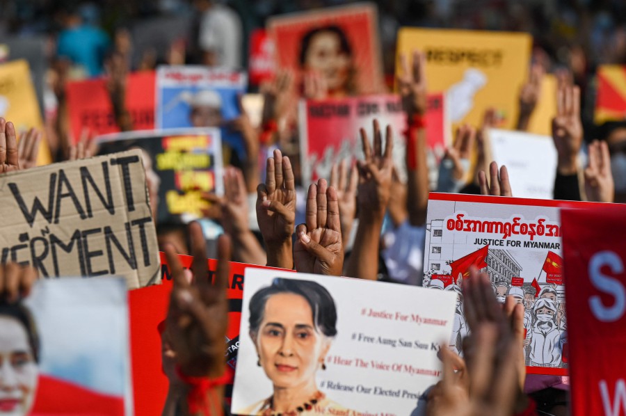 Protesters hold up the three finger salute with signs calling for the release of detained Myanmar civilian leader Aung San Suu Kyi during a demonstration against the military coup in Yangon on Feb 16. - AFP pic