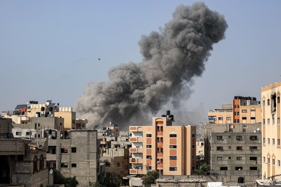 A bird flies past a plume of smoke towering during Israeli bombardment in Gaza City. (Photo by AFP)