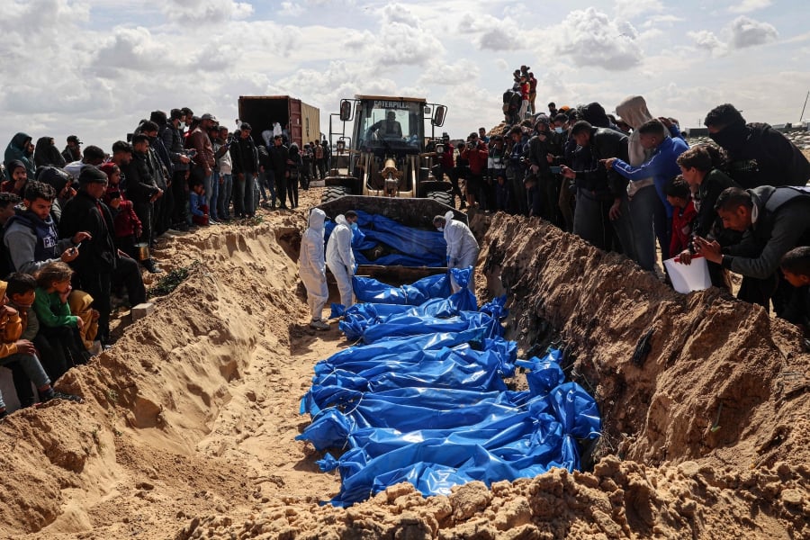 Mourners watch as medical personnel prepare the bodies of 47 Palestinians, that were taken and later released by Israel, during a mass funeral in Rafah in the southern Gaza Strip. (Photo by SAID KHATIB / AFP)