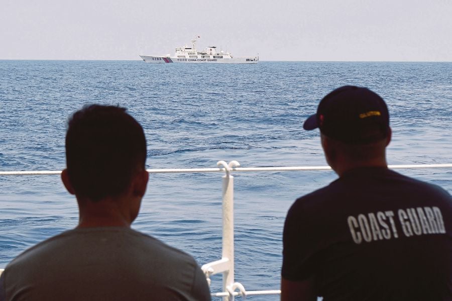 Philippine Coast Guard personnel aboard BRP Bagacay observe a China Coast Guard ship during the distribution of fuel and food to fishers by the civilian-led mission Atin Ito (This Is Ours) Coalition, in the disputed South China Sea. (Photo by Ted ALJIBE / AFP)