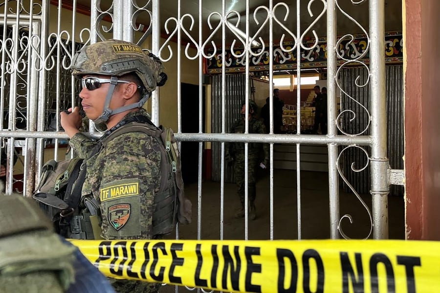 Military personnel stand guard at the entrance of a gymnasium while police investigators look for evidence after a bomb attack at Mindanao State University in Marawi, Lanao del sur province. (Photo by Merlyn MANOS / AFP)
