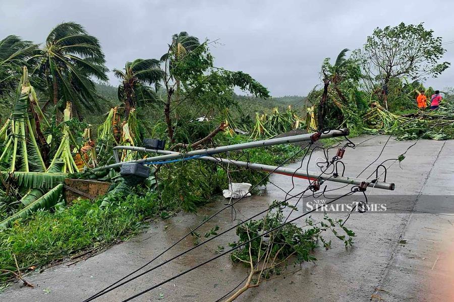 A fallen electric post blocks a road after tropical storm Molave hit the town of Pola, Oriental Mindoro province, yesterday. (Photo by Erik DE CASTRO / AFP)
