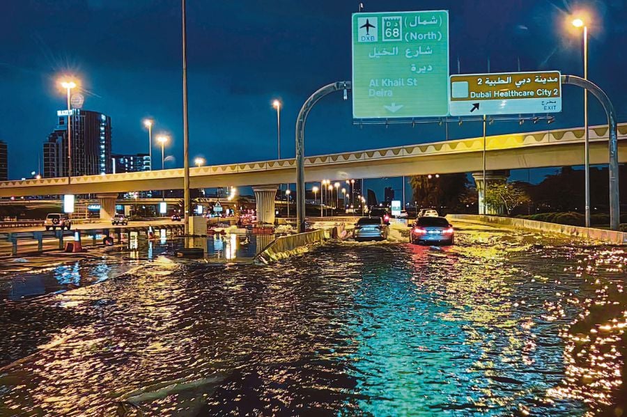 Motorisits drive along a flooded street following heavy rains in Dubai. (Photo by Giuseppe CACACE / AFP)