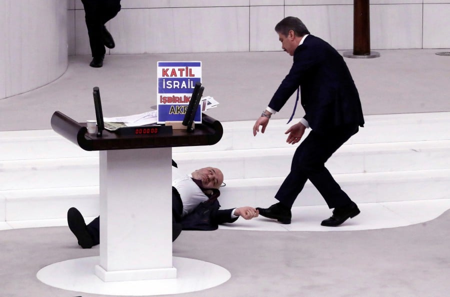 Turkey's opposition Felicity Party (Saadet) lawmaker Hasan Bitmez lies on the floor next to a stand with a placard after collapsing following his speech criticizing the government's policy towards Israel, at the Turkish parliament in Ankara, Turkey December 12, 2023. The placard reads: "Murderer Israel, collaborator AK Party". REUTERS PIC