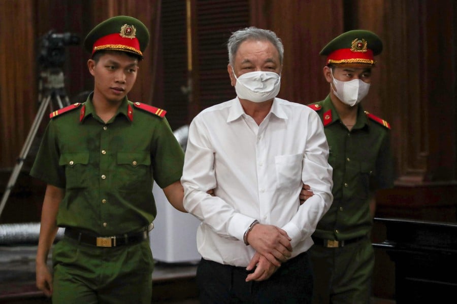 Vietnamese soft drink boss Tran Qui Thanh (Centre) being led into a court in Ho Chi Minh City today (April 25). Thanh appeared in court today in a USD40 million fraud case -- the latest high-profile business figure snared in the country's wide-ranging crackdown on corruption. — AFP