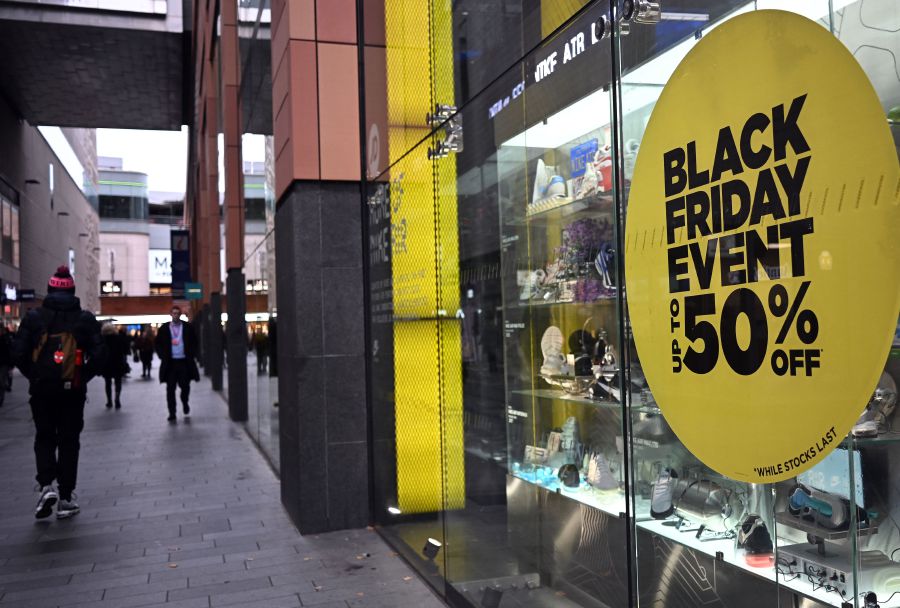 Pedestrians walk past a store with a Black Friday discount promotion in it's window, in Liverpool, north west England. - AFP pic 