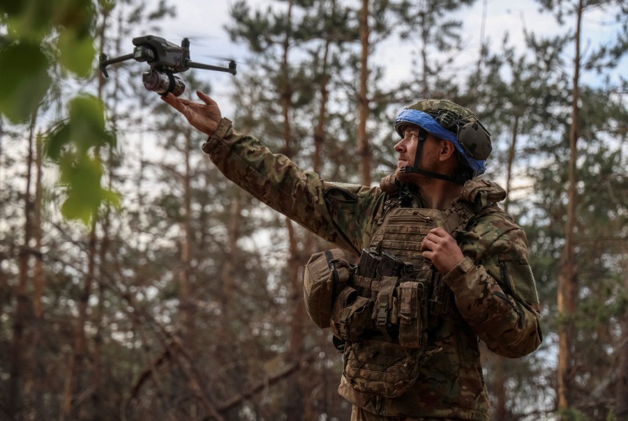 A serviceman of the 95th Separate Air Assault Brigade of the Armed Forces of Ukraine launches a drone with a grenade attached to it, to fly it over the positions of Russian troops, amid Russia's attack on Ukraine, at a frontline in the Donbas region, May 27, 2024. REUTERS