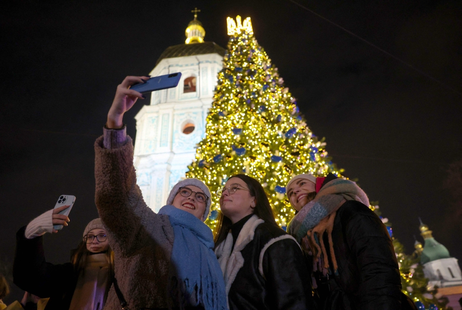 People take a selfie as they attend the inauguration ceremony of the Christmas tree on Sophia Square in Kyiv. (Photo by Anatolii STEPANOV / AFP)