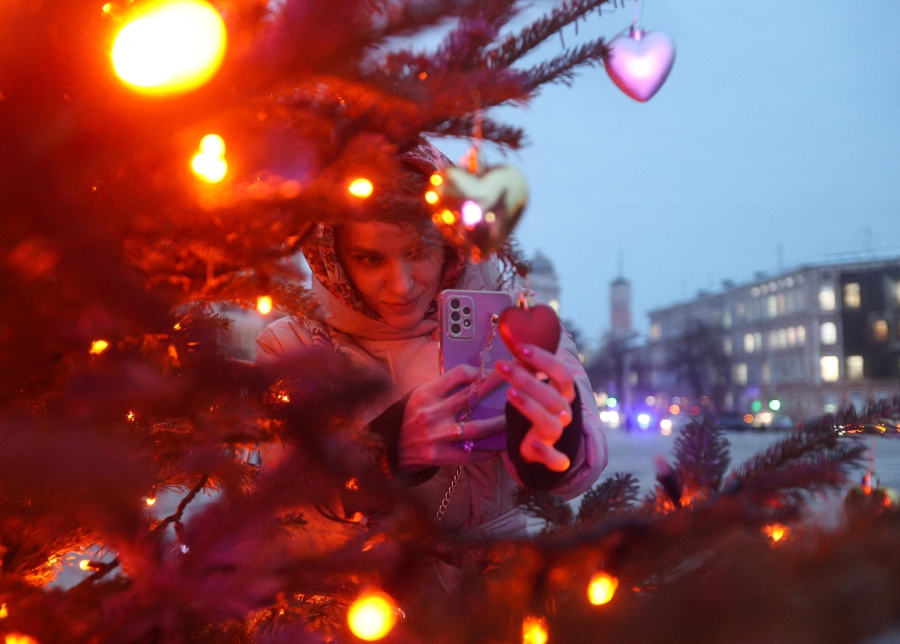 A woman takes a photograph of Christmas decorations before the inauguration ceremony of the Christmas tree on Sophia Square in Kyiv. (Photo by Anatolii STEPANOV / AFP)