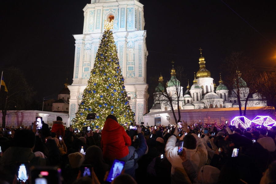 People take photographs as they attend the inauguration ceremony of the Christmas tree on Sophia Square in Kyiv, amid the Russian invasion of Ukraine. (Photo by Anatolii STEPANOV / AFP)