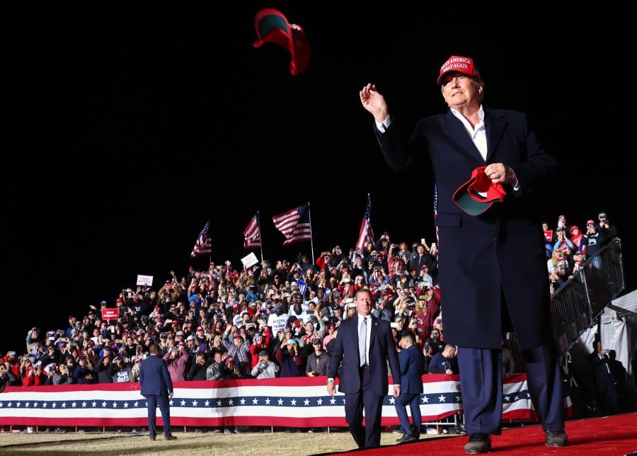 FLORENCE, ARIZONA: Former President Donald Trump tosses a MAGA hat to the crowd before speaking at a rally at the Canyon Moon Ranch festival grounds on January 15, 2022 in Florence, Arizona. The rally marks Trump's first of the midterm election year with races for both the U.S. Senate and governor in Arizona this year. - Mario Tama/Getty Images/AFP