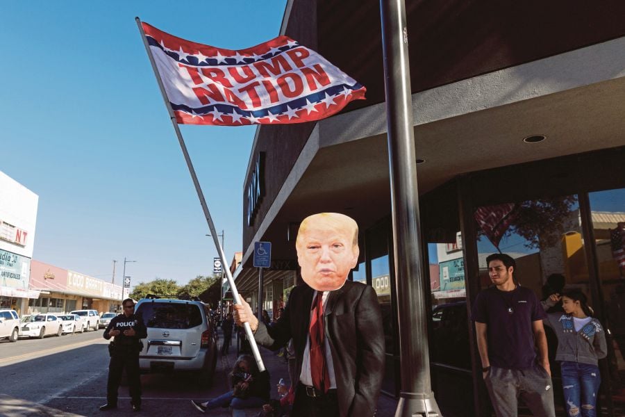A man dressed up like Donald Trump and waved a pro-Trump flag across the street from local border and immigration activists protesting Texas Gov. Abbott and several other governors' visit to Shelby Park for a news conference. (Photo by Michael Gonzalez / GETTY IMAGES NORTH AMERICA / Getty Images via AFP)