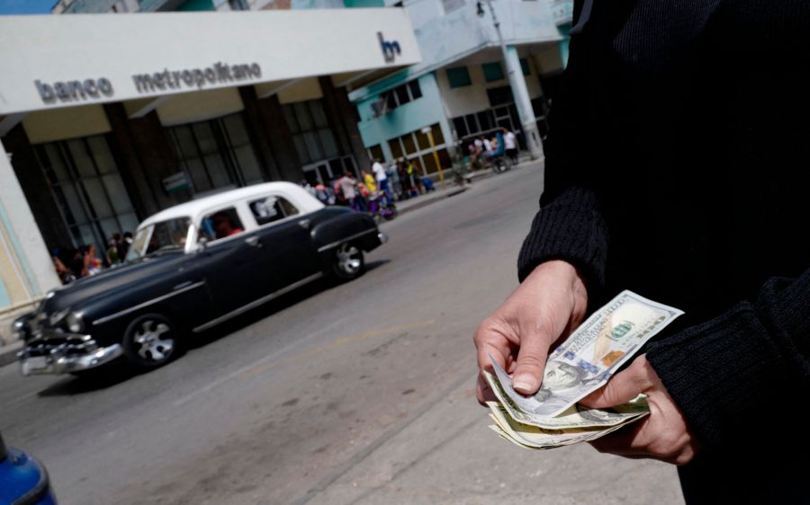 A person shows US dollars outside a bank in Havanat, a day after the Cuban government announced a surprise reversal of a US dollar deposit ban. (Photo by Adalberto ROQUE / AFP)