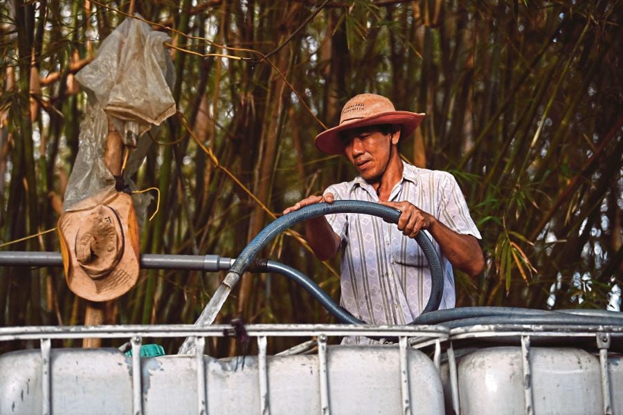 Farmer Nguyen Van Hung fills fresh water into a tank for sale, in Vietnam's southern Ben Tre province. (Photo by Nhac NGUYEN / AFP)