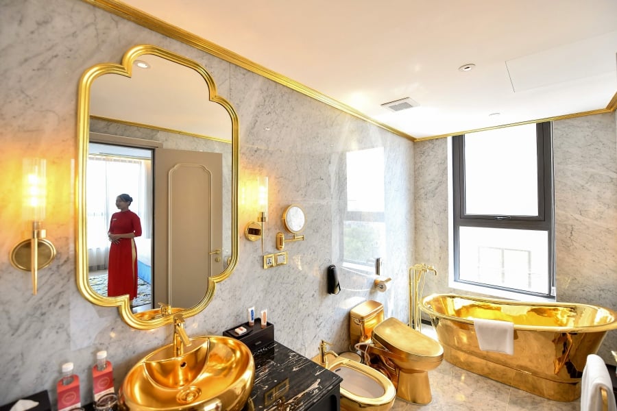 A staff member poses for a photograph inside the 1,000 USD per night executive two bedroom suite of the newly-inaugurated Dolce Hanoi Golden Lake hotel, the world's first gold-plated hotel, in Hanoi. (Photo by Manan VATSYAYANA / AFP)