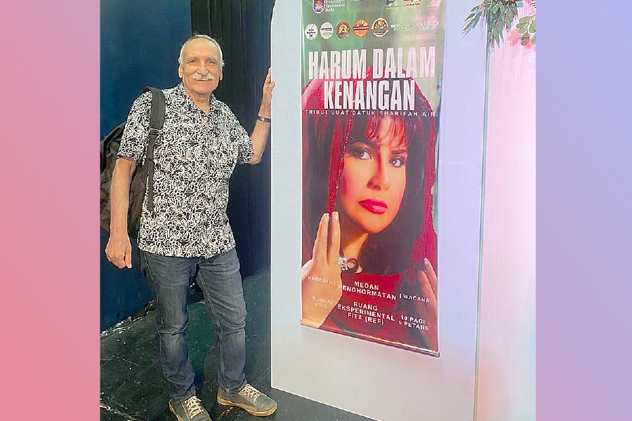The writer standing next to a poster featuring Datuk Sharifah Aini at a seminar at Universiti Teknologi Mara. - Pic from Writer