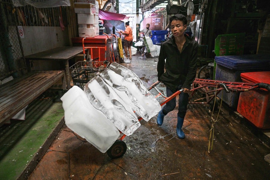 FILE: A worker transports blocks of ice through a fresh market on a hot day in Bangkok on April 18. Thai authorities issued an extreme heat warning for Bangkok on yesterday (April 24) urging people to stay indoors for their own safety as temperatures soared. — AFP