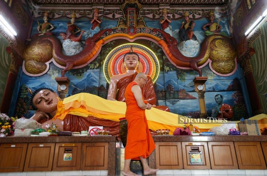 A monk from the Mahindarama Buddhist Temple (Theravada) at Jalan Kampar putting a final touch to sleeping buddha statue for Wesak Day Celebration. - NSTP/MIKAIL ONG